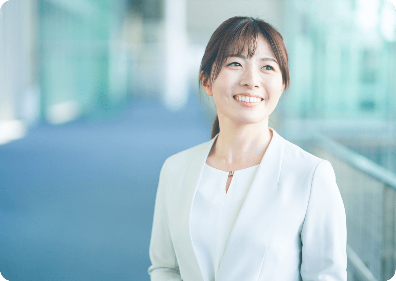 オフィスの廊下で笑顔を見せる女性スタッフのポートレート写真