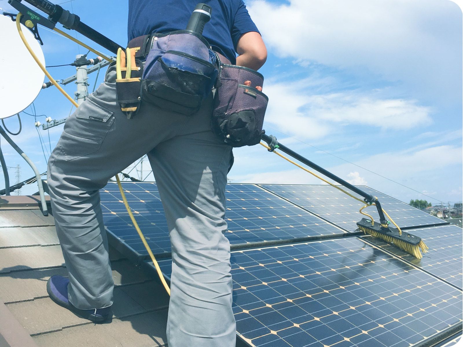 ヘルメットと手袋を着用した技術者が、マルチメーターを使って電気制御盤を点検している様子